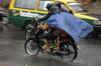 Naik motor dengan jas hujan
